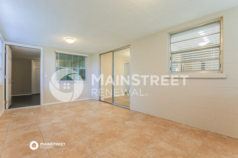 a large living room with tile floors and a door to a hallway
