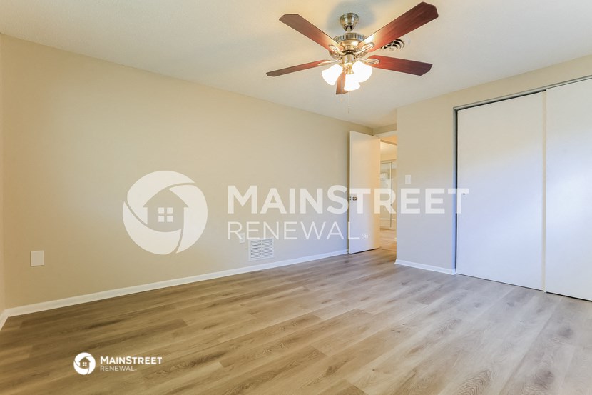 a living room with a large window and a ceiling fan