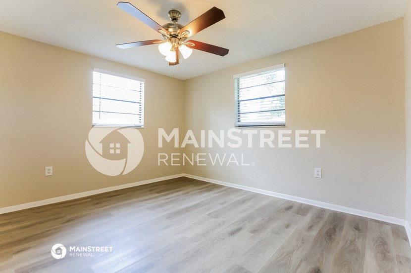 a bedroom with a large window and a ceiling fan