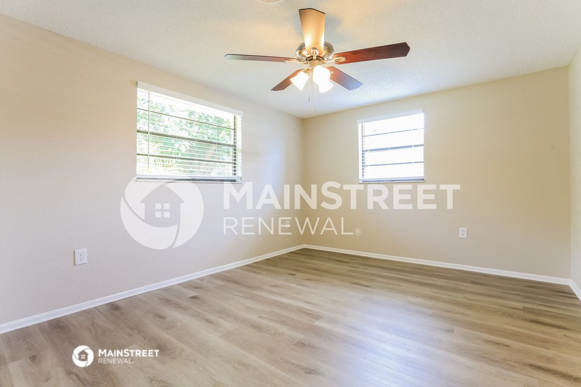 an empty living room with a ceiling fan and a window