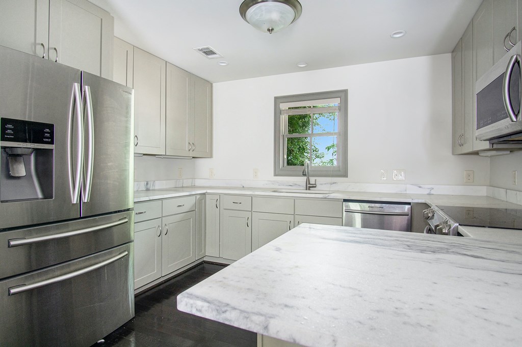 A kitchen with a marble counter top and stainless steel appliances.