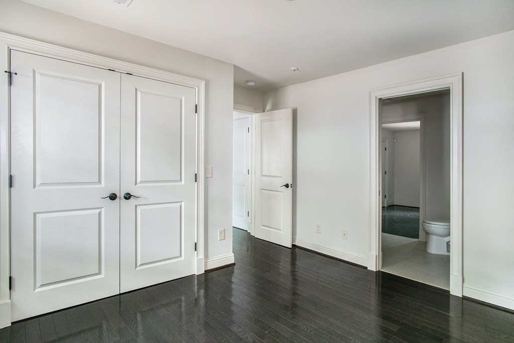 A room with white doors and a toilet visible through one of them.