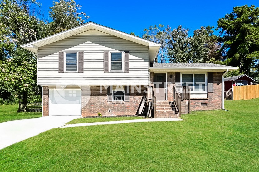 a white and brick house with a lawn and a driveway