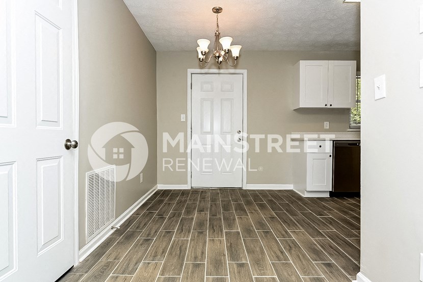 a kitchen and entryway with a white door and white cabinets