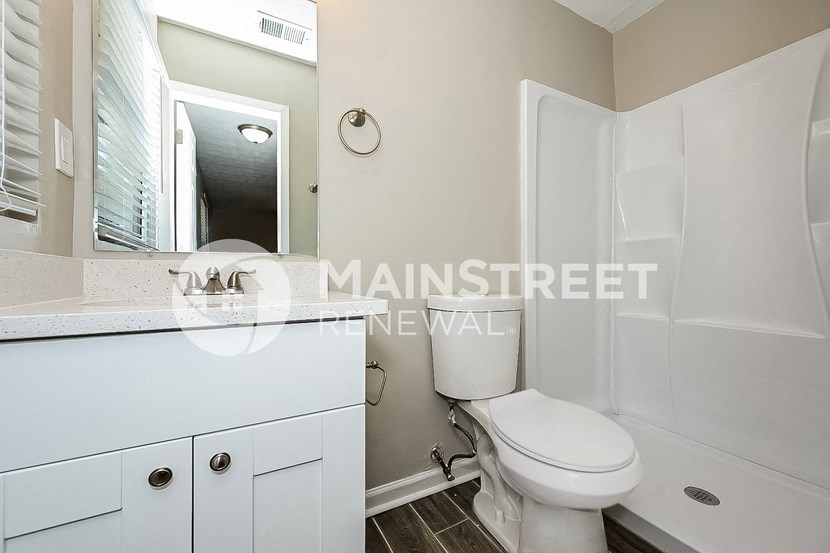 a white bathroom with a toilet and a sink and a mirror