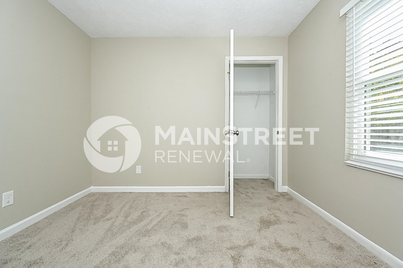 a bedroom with a closet and a carpeted floor