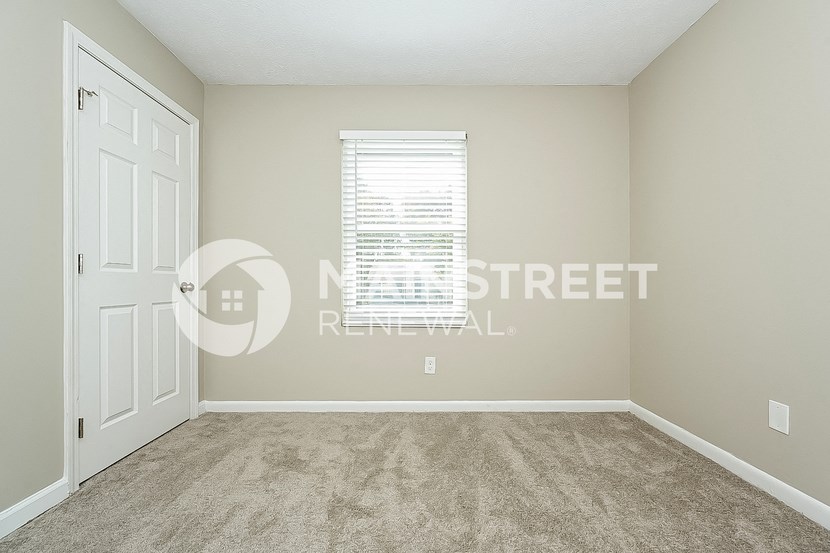 a bedroom with a carpeted floor and a white door