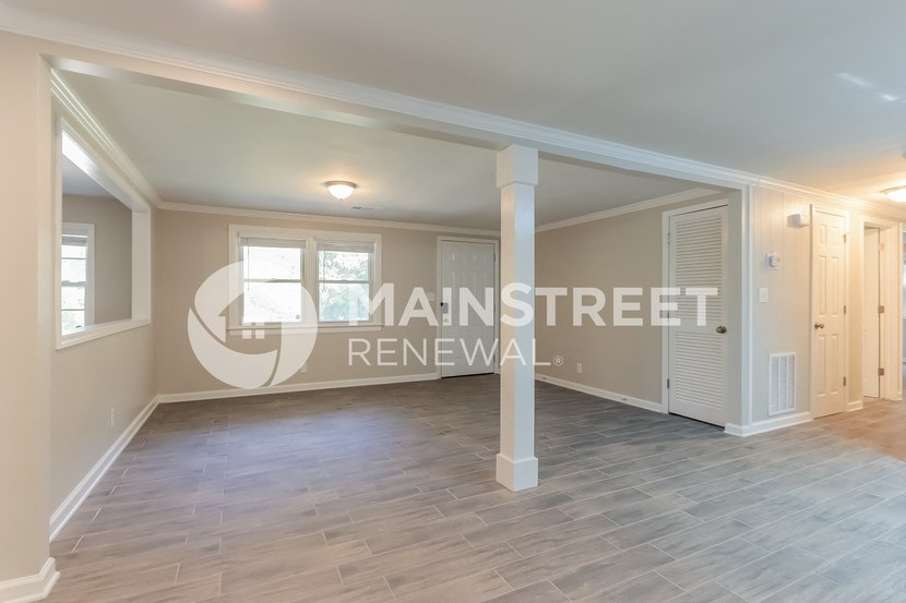 a renovated living room with white pillars and a hard wood floor