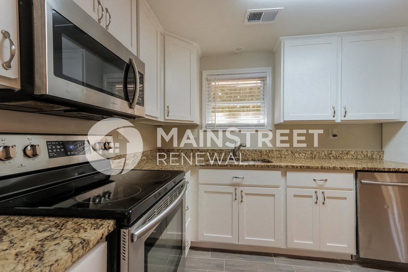 a kitchen with white cabinets and granite counter tops