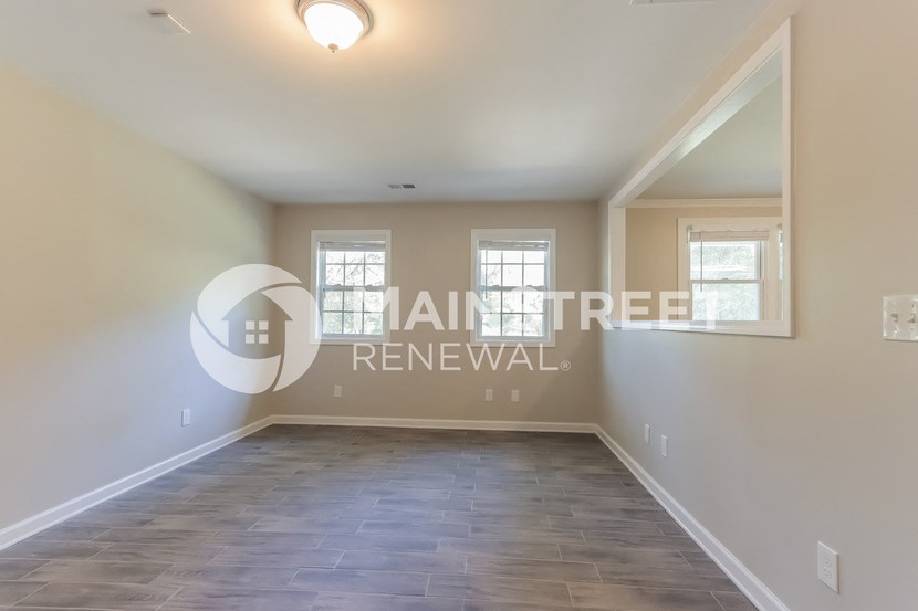 a large empty room with a hardwood floor and a window