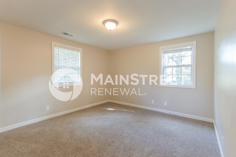 a bedroom with a carpeted floor and two windows