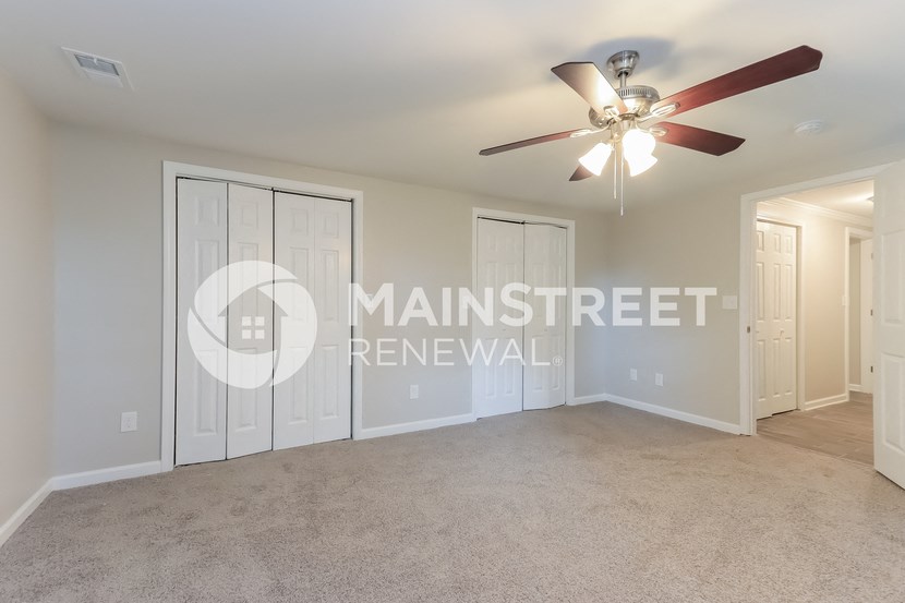 a living room with carpet and a ceiling fan