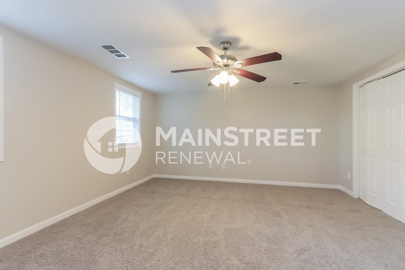a living room with carpet and a ceiling fan