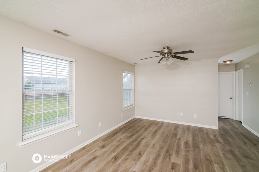 the spacious living room with hardwood floors and a ceiling fan