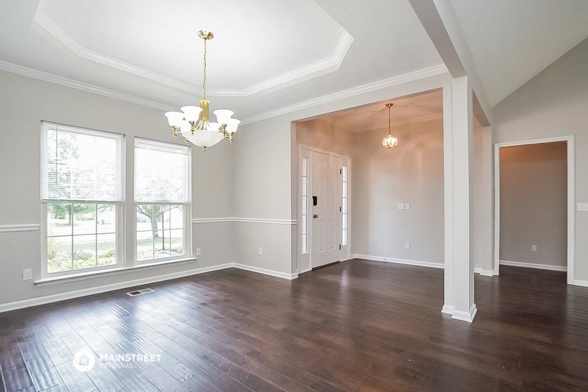 an empty living room with hardwood flooring and large windows
