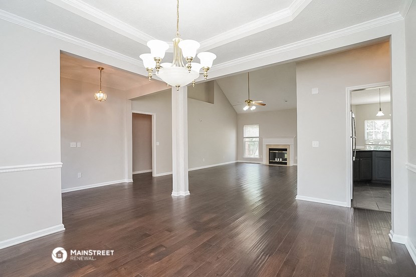 an empty living room with hardwood floors and a chandelier