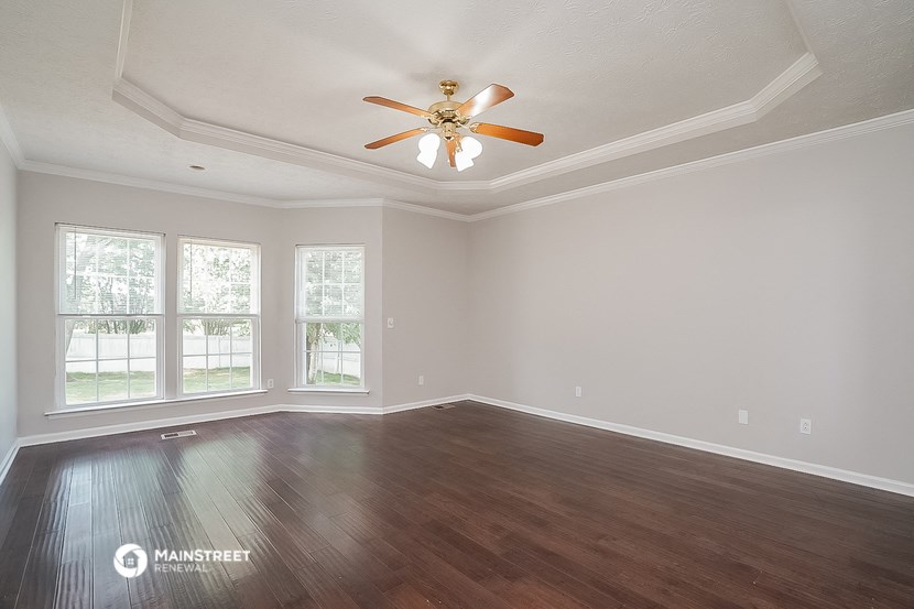 an empty living room with a ceiling fan and wood floors