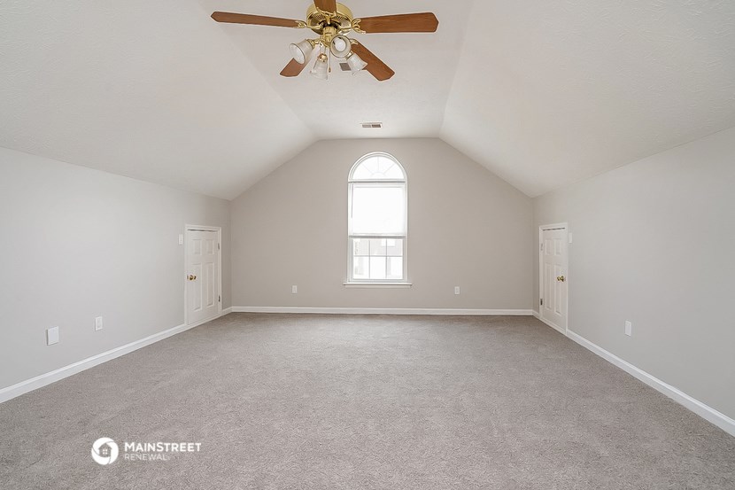 the master bedroom with vaulted ceilings and a ceiling fan