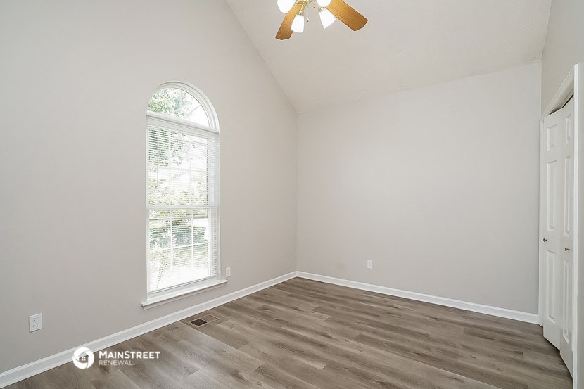 the spacious living room with wood flooring and a ceiling fan