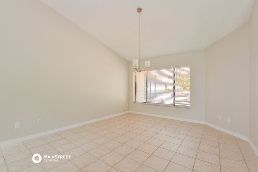 an empty living room with a large window and tiled flooring
