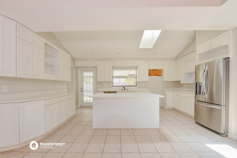 a large white kitchen with a large island and stainless steel appliances
