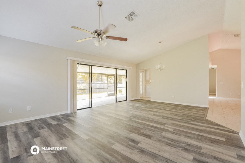 the living room and dining room with wood flooring and a ceiling fan
