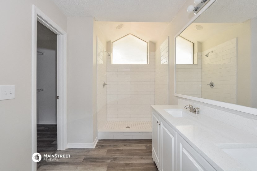 a white bathroom with a large mirror and a shower