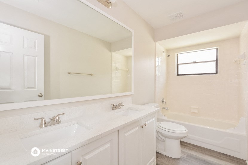 a white bathroom with a large mirror and a toilet and a sink