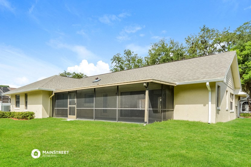 a home with a screened in porch and a grass yard