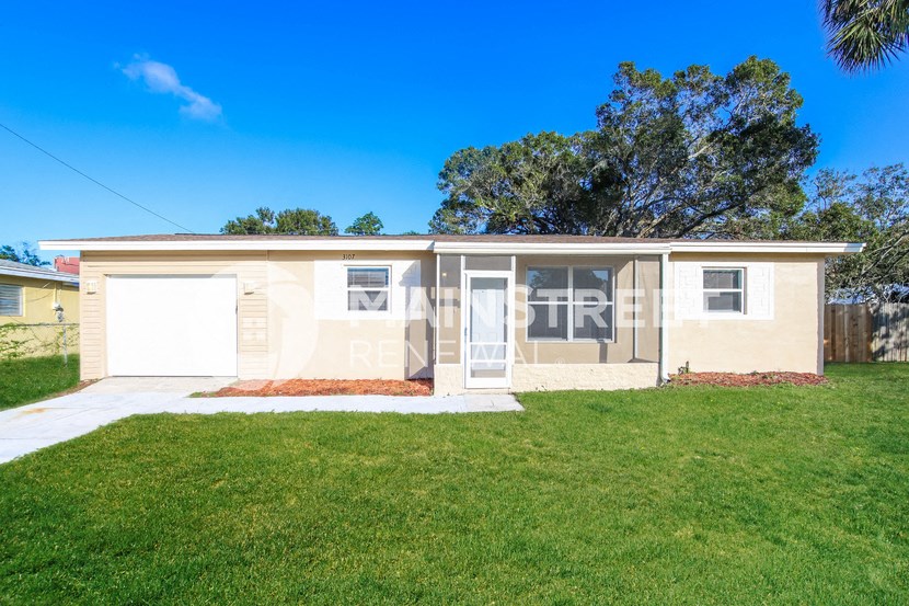 a small tan house with a lawn and a garage