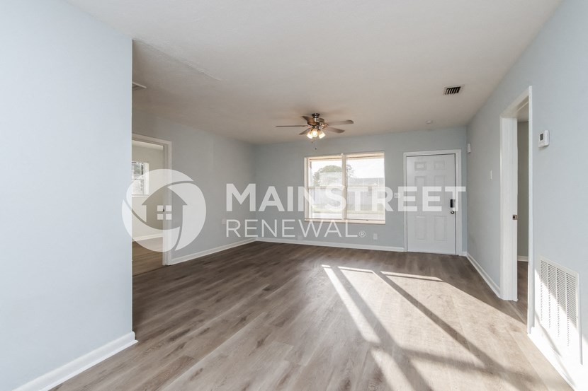 a renovated living room with white walls and hardwood floors