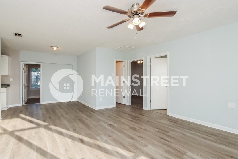 a renovated living room with wood floors and a ceiling fan