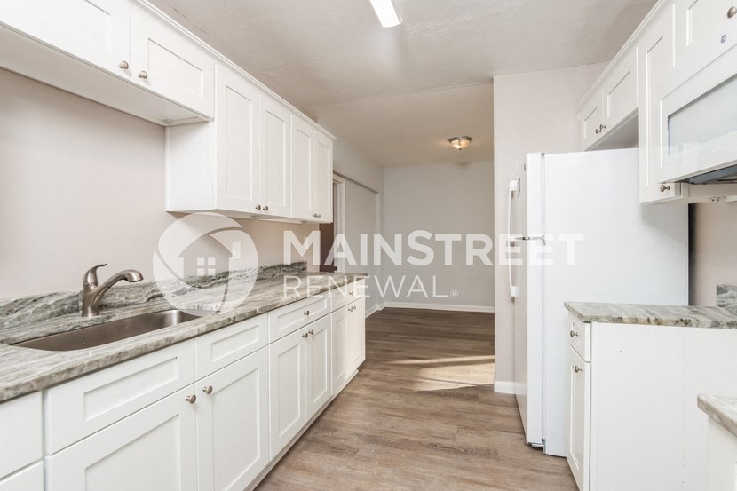 a renovated kitchen with white cabinets and a stainless steel sink