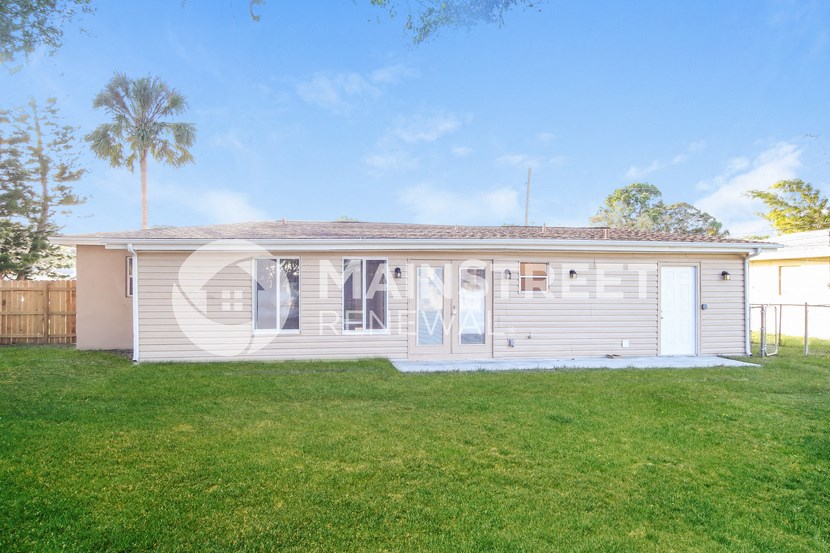 a small house with a lawn and a palm tree