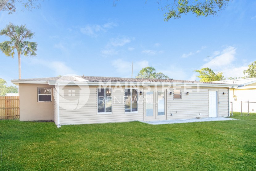 a small white house with a lawn and a palm tree