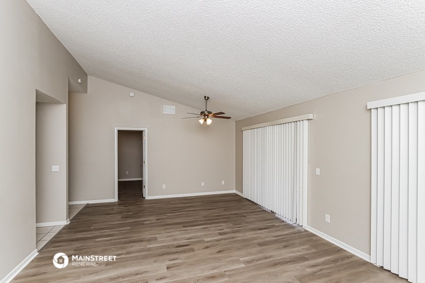the spacious living room with sliding closet doors and a ceiling fan
