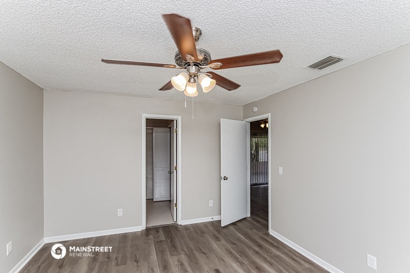 a living room with a ceiling fan and a door to a hallway
