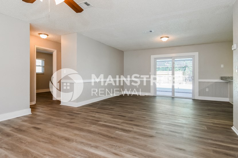 a renovated living room with a hardwood floor and a door to a patio