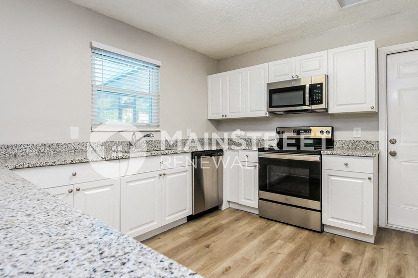 a kitchen with granite counter tops and white cabinets