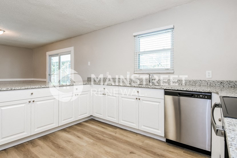 an empty kitchen with white cabinets and a counter top and a stainless steel dishwasher