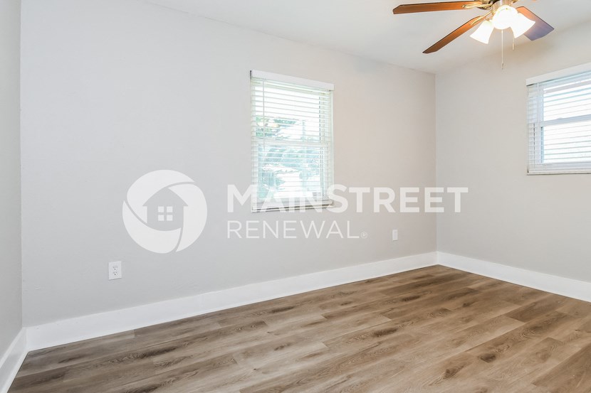 a bedroom with a hardwood floor and white walls