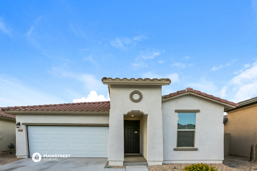 a white house with a garage door and a blue sky