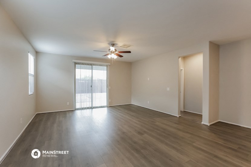 an empty living room with wood flooring and a ceiling fan