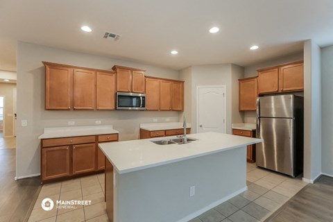 a kitchen with a white counter top and wooden cabinets and a stainless steel refrigerator
