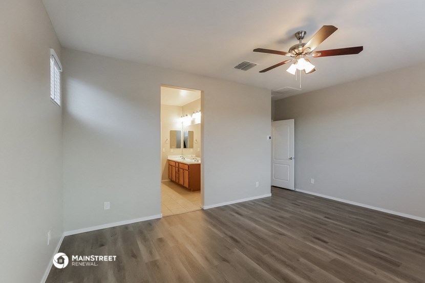 an empty living room with a ceiling fan and a bathroom