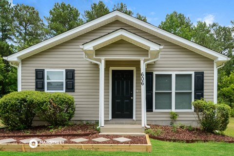 a small gray house with a black front door