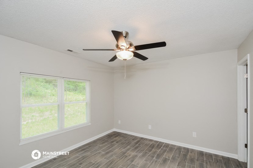 the spacious living room with ceiling fan and window