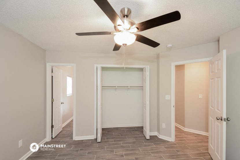 an empty living room with a ceiling fan and a closet