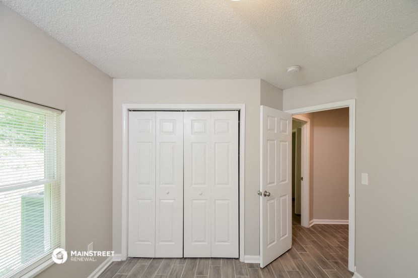 the spacious living room with two closets and a door to the hallway
