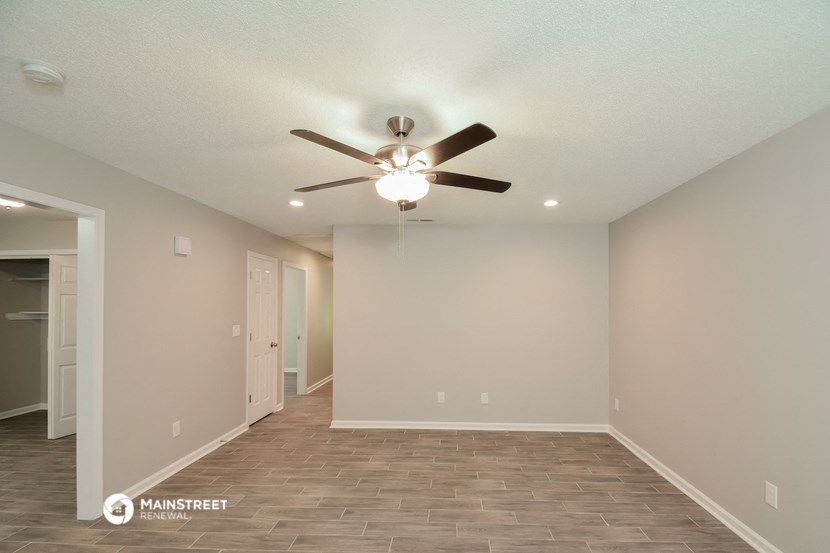 the spacious living room with ceiling fan and wood flooring